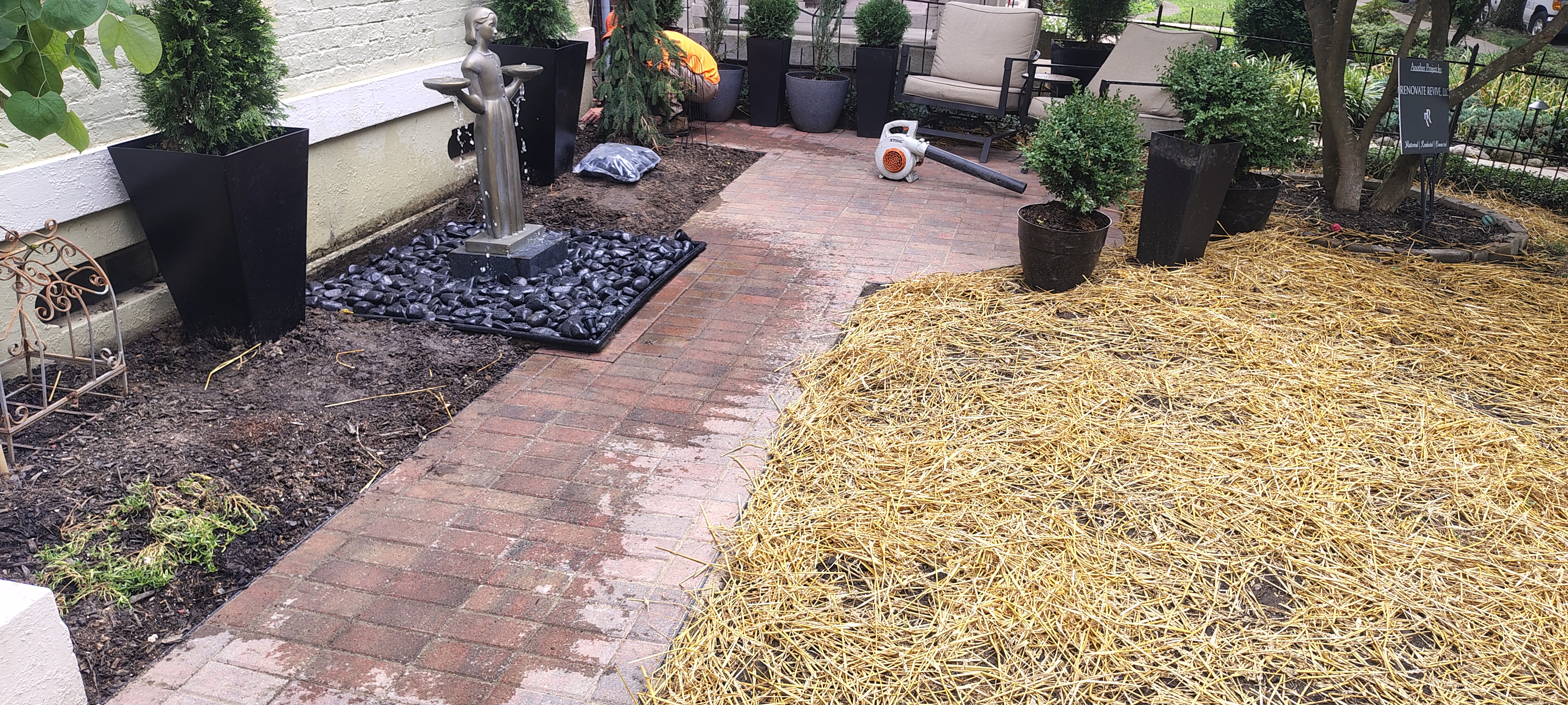 Brick paver patio with a decorative water feature and surrounding landscape